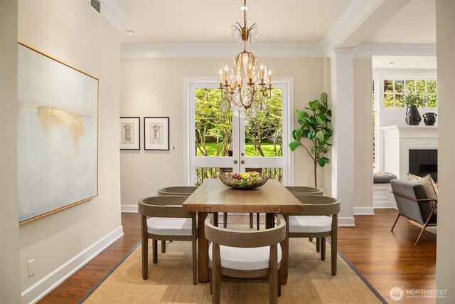 dining room with a chandelier, crown molding, wood finished floors, a fireplace, and baseboards