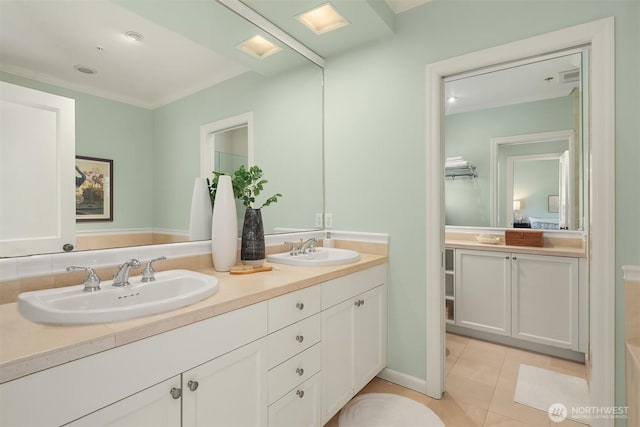 ensuite bathroom with tile patterned floors, double vanity, and crown molding