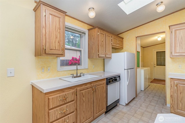 kitchen with white appliances, a sink, separate washer and dryer, vaulted ceiling, and a skylight