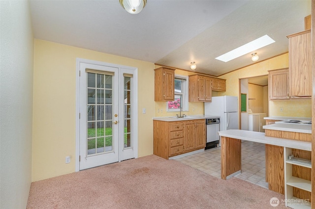 kitchen featuring a sink, lofted ceiling, a skylight, white appliances, and light countertops