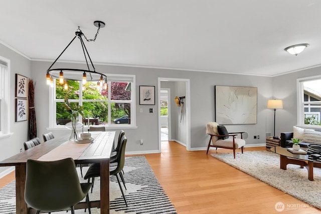 dining room featuring light wood-style floors, crown molding, baseboards, and a chandelier