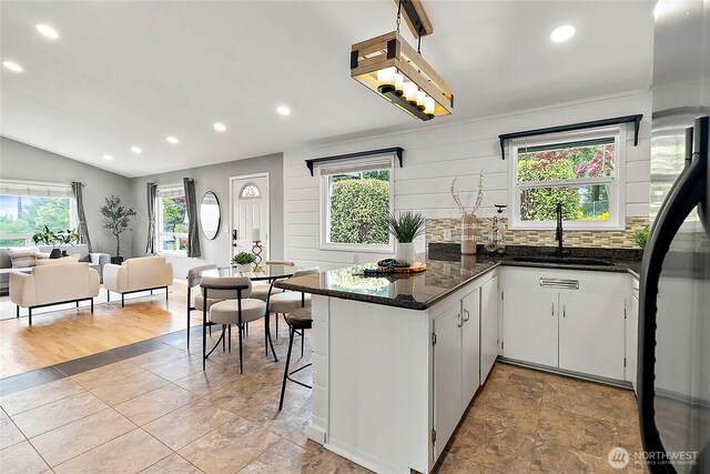 kitchen featuring a sink, recessed lighting, plenty of natural light, freestanding refrigerator, and a peninsula