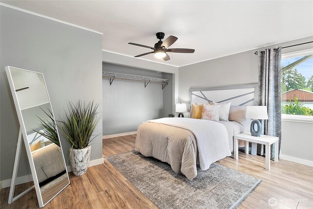 bedroom featuring baseboards, wood finished floors, and a ceiling fan
