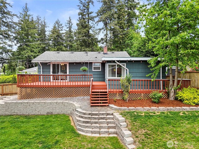 rear view of house featuring a wooden deck, a shingled roof, and a chimney