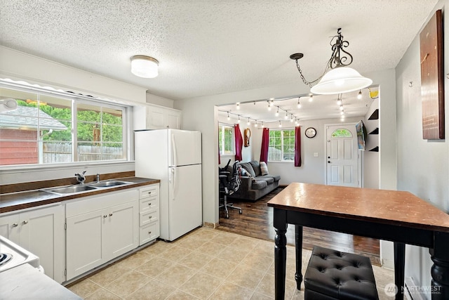714 S 43rd St, Tacoma, WA 98418 - kitchen featuring freestanding refrigerator, dark countertops, rail lighting, a textured ceiling, and white cabinetry