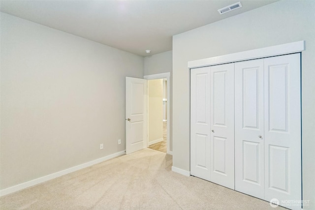 unfurnished bedroom with light carpet, baseboards, and a closet