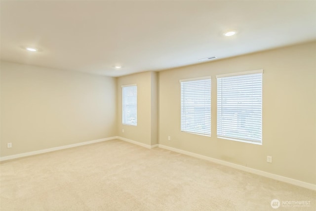 spare room featuring light carpet, recessed lighting, plenty of natural light, and baseboards