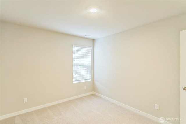 spare room featuring baseboards and light carpet