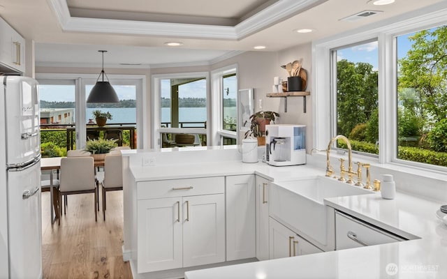 725 1st St S Unit 104, Kirkland, WA 98033 - kitchen with freestanding refrigerator, a sink, crown molding, a peninsula, and a water view