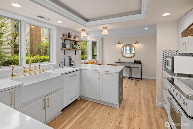 725 1st St S Unit 104, Kirkland, WA 98033 - kitchen featuring a sink, white appliances, a peninsula, crown molding, and light wood-style flooring