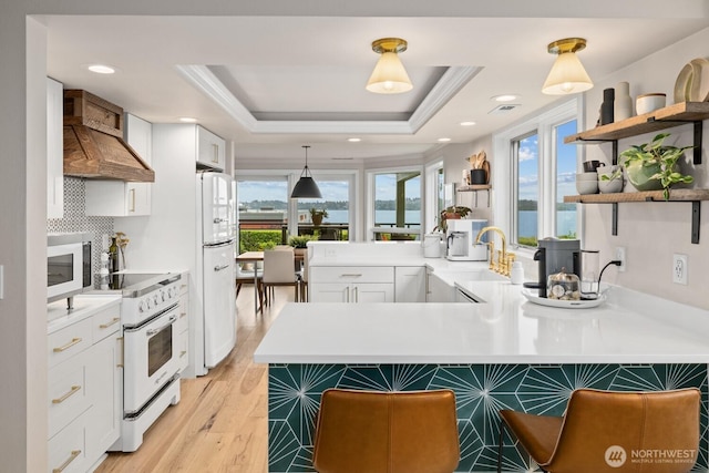 725 1st St S Unit 104, Kirkland, WA 98033 - kitchen featuring white appliances, custom exhaust hood, open shelves, white cabinetry, and a peninsula