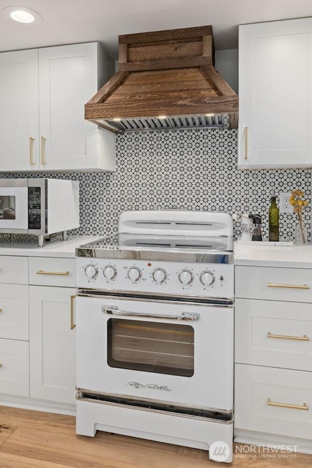 725 1st St S Unit 104, Kirkland, WA 98033 - kitchen with electric stove, premium range hood, light countertops, tasteful backsplash, and white cabinetry