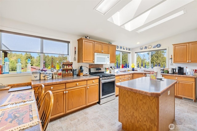 399 Pike Pl, Sequim, WA 98382 - kitchen featuring stainless steel gas range oven, white microwave, a skylight, vaulted ceiling, and a center island