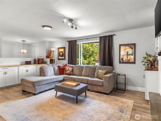 5431 Anton Ct SE, Olympia, WA 98501 - living room with light wood-style floors, a textured ceiling, a chandelier, baseboards, and track lighting