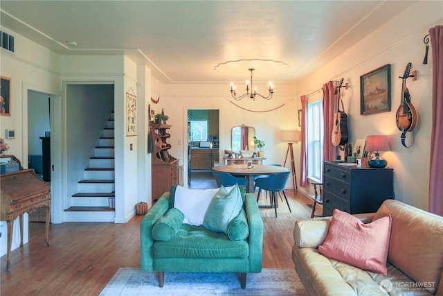 living area featuring a chandelier, stairway, wood finished floors, and healthy amount of natural light