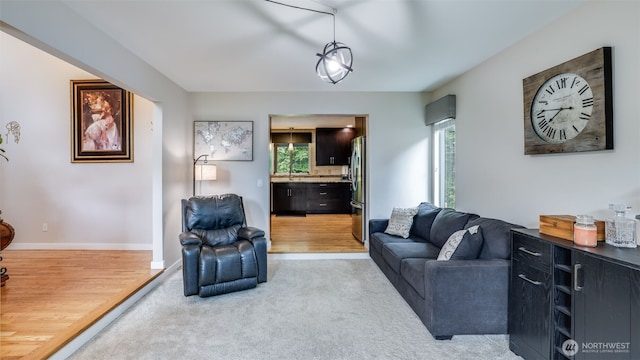 living room featuring plenty of natural light, light colored carpet, baseboards, and light wood-type flooring