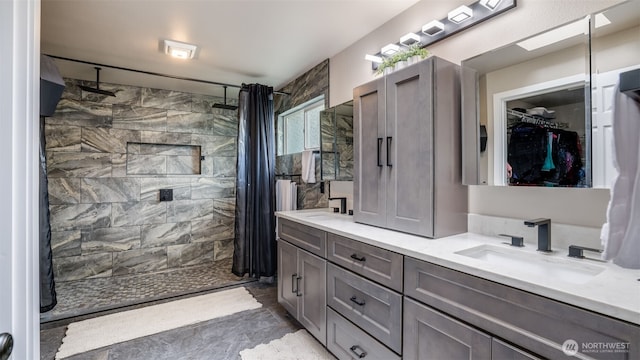 full bath featuring double vanity, a stall shower, and a walk in closet