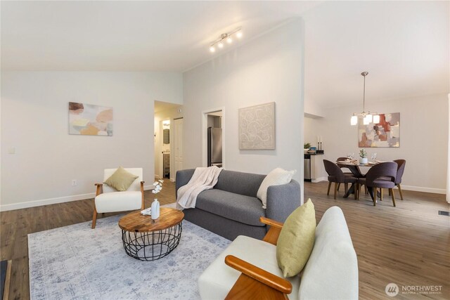 living room with vaulted ceiling, baseboards, wood finished floors, and a chandelier