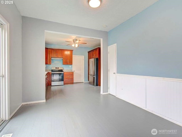 823 D St, Vader, WA 98593 - kitchen featuring appliances with stainless steel finishes, light countertops, ceiling fan, brown cabinetry, and wainscoting