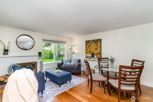 living area with wood finished floors, a brick fireplace, and baseboards