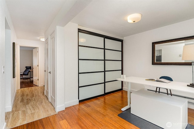 office space with light wood-type flooring and baseboards