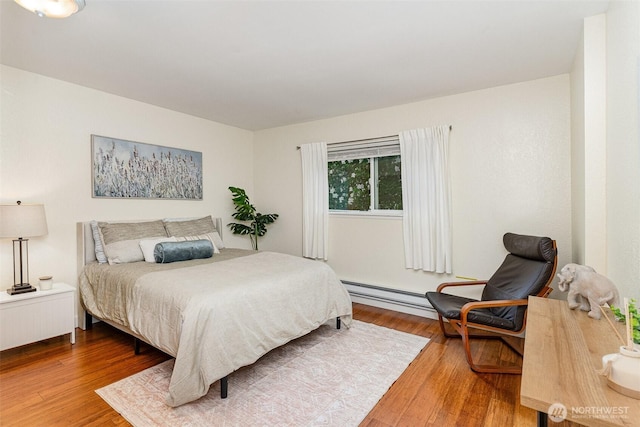 bedroom featuring wood finished floors and a baseboard heating unit
