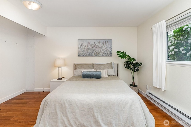 bedroom featuring a baseboard radiator, wood finished floors, and baseboards