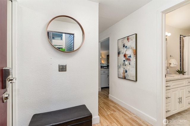 hall featuring light wood finished floors and baseboards