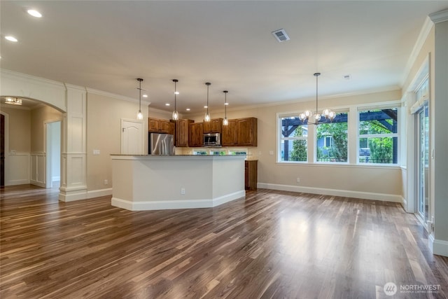 711 SE Pheasant Run, College Place, WA 99324 - kitchen featuring appliances with stainless steel finishes, arched walkways, wood finished floors, brown cabinets, and a kitchen island with sink