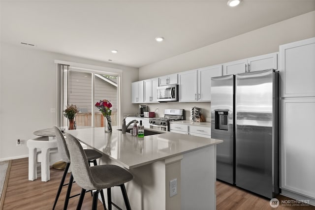 7810 22nd Trl SE, Lacey, WA 98503 - kitchen with stainless steel appliances, a sink, a breakfast bar, a center island with sink, and white cabinetry