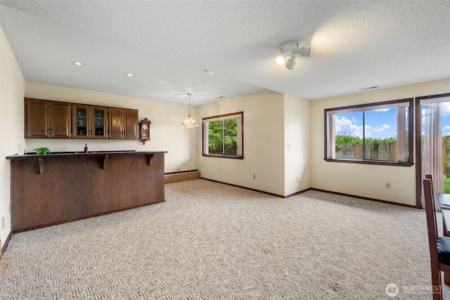 916 Kari Ln, Steilacoom, WA 98388 - kitchen featuring a breakfast bar area, light colored carpet, baseboards, a peninsula, and glass insert cabinets