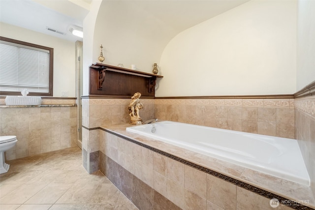 916 Kari Ln, Steilacoom, WA 98388 - bathroom featuring toilet, a garden tub, tile patterned floors, wainscoting, and tile walls