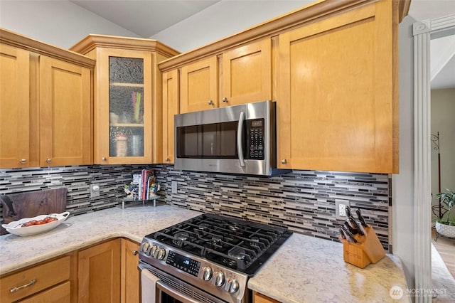 2557 Captains Ct, Ferndale, WA 98248 - kitchen featuring stainless steel appliances, decorative backsplash, glass insert cabinets, light stone counters, and vaulted ceiling