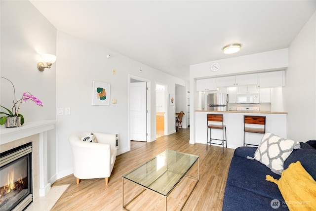 2331 42nd Ave SW Unit 403, Seattle, WA 98116 - living area featuring light wood-style floors, a tiled fireplace, and baseboards