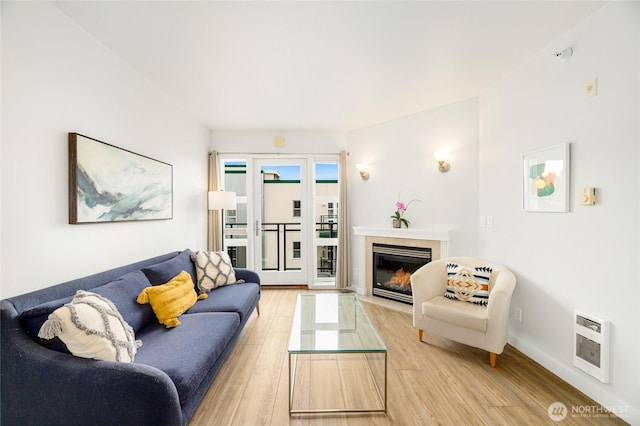 2331 42nd Ave SW Unit 403, Seattle, WA 98116 - living room featuring heating unit, light wood-type flooring, a fireplace, and baseboards