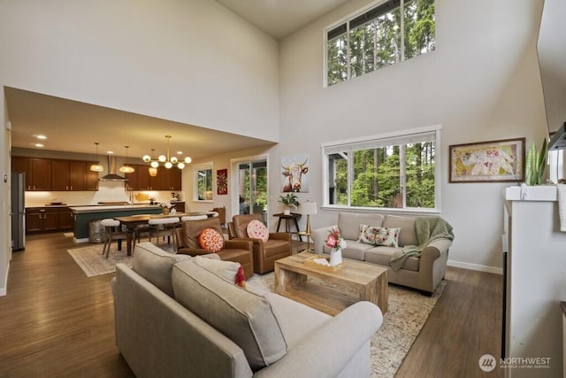 4471 Hales Ct SW, Port Orchard, WA 98367 - living room featuring a towering ceiling, dark wood-style flooring, a chandelier, and baseboards