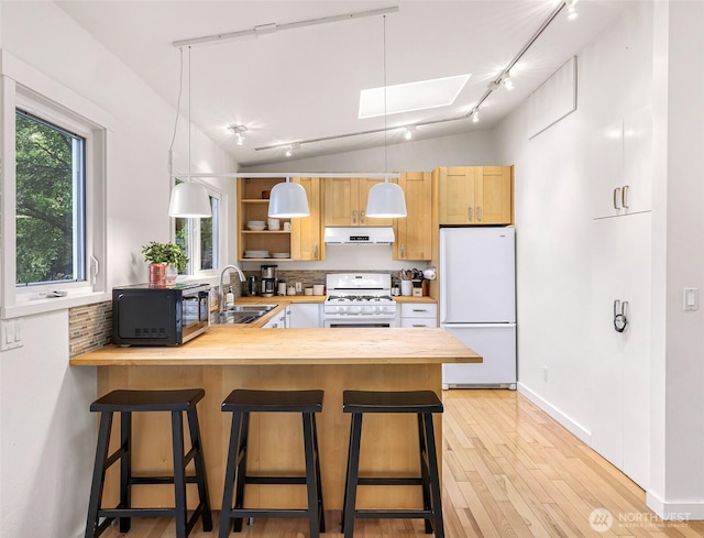 2920 Cedar Ave, Lummi Island, WA 98262 - kitchen with white appliances, ventilation hood, track lighting, a peninsula, and a skylight