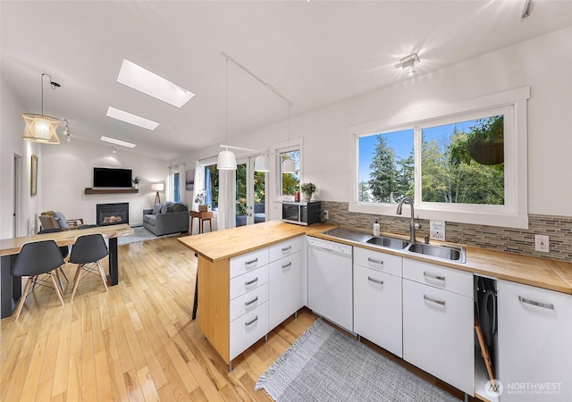 2920 Cedar Ave, Lummi Island, WA 98262 - kitchen featuring butcher block countertops, white dishwasher, a fireplace, a peninsula, and tasteful backsplash