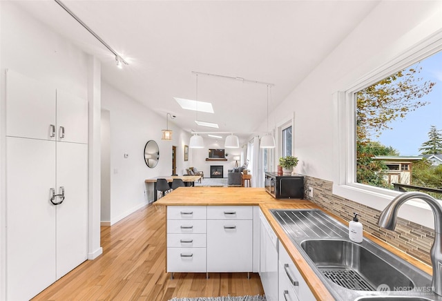 2920 Cedar Ave, Lummi Island, WA 98262 - kitchen with wooden counters, a skylight, tasteful backsplash, a peninsula, and white cabinets