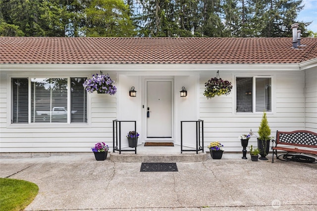 entrance to property featuring a tile roof and a patio area