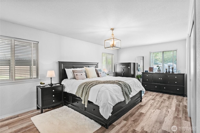 bedroom featuring multiple windows, wood finished floors, a chandelier, and baseboards