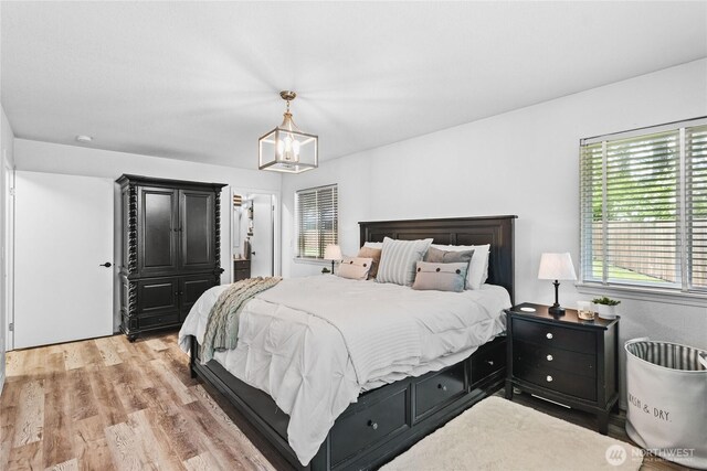 bedroom featuring multiple windows, a chandelier, and light wood-type flooring