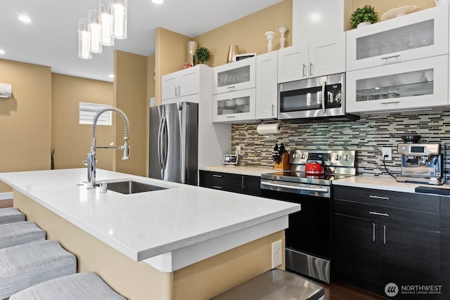 2311 S 135th Ln, Seattle, WA 98168 - kitchen with appliances with stainless steel finishes, a sink, decorative backsplash, a center island with sink, and recessed lighting