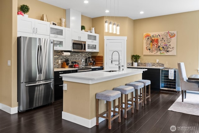 2311 S 135th Ln, Seattle, WA 98168 - kitchen with stainless steel appliances, a sink, wine cooler, dark wood-style flooring, and a center island with sink