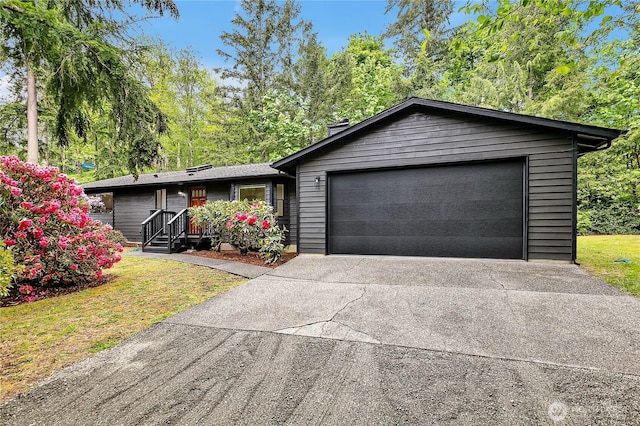 single story home with driveway, an attached garage, a chimney, and a front lawn