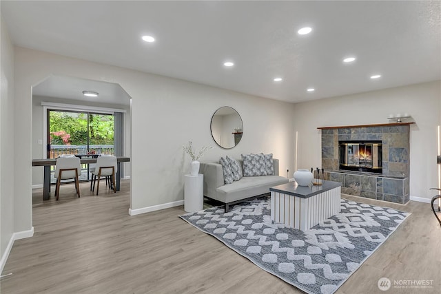 living area featuring wood finished floors, baseboards, a tile fireplace, and recessed lighting