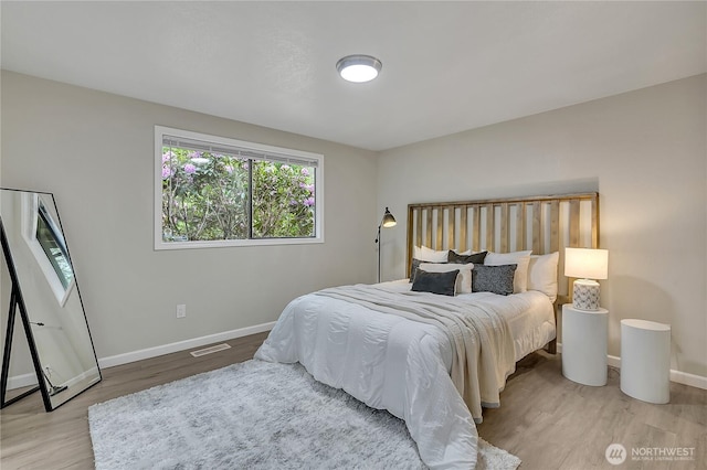 bedroom featuring wood finished floors, multiple windows, and baseboards