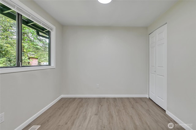 empty room with light wood-style flooring, healthy amount of natural light, and baseboards