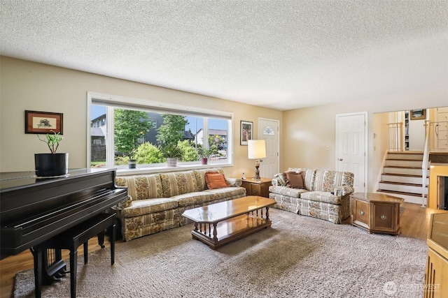 living area with a textured ceiling, carpet floors, and stairway