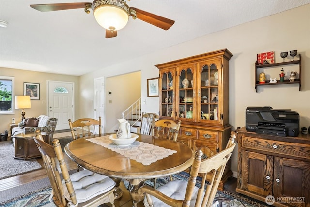 dining space with ceiling fan, stairs, and wood finished floors